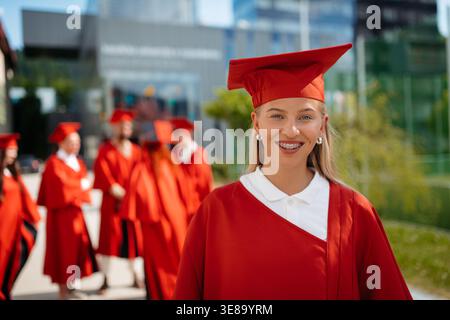 Sorridente giovane laureata in berretto e abito durante la cerimonia di laurea universitaria. Foto Stock