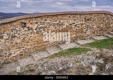 Muro di bastioni in pietra ricurvo restaurato con mattoni e abbraccio nella fortezza medievale di Rupea in Transilvania, Romania Foto Stock