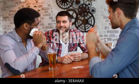 Migliori amici giocando a carte, avente il resto in bar Foto Stock