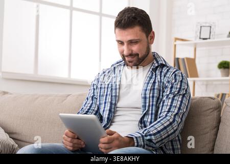 Giovane che legge un articolo online su un tablet digitale Foto Stock