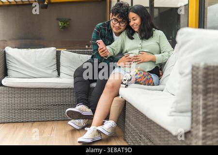 Aspettatevi una coppia che si rilassa in un patio all'aperto guardando lo schermo di uno smartphone Foto Stock