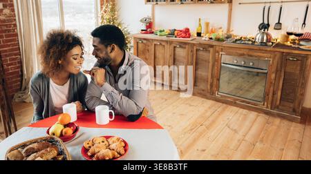 African-american giovane godendo gustosi biscotti in cucina Foto Stock