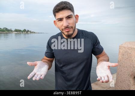 Uomo con polvere di gesso sulle mani che si prepara per una routine di fitness all'aperto vicino all'acqua Foto Stock