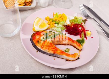 Bistecca di salmone arrosto con salsa verde, verdure e limone Foto Stock