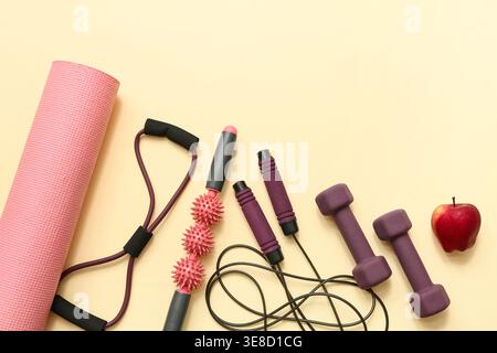 Apple e diverse attrezzature sportive sullo sfondo beige Foto Stock