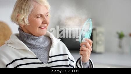 Donna anziana che usa il nebulizzatore a casa Foto Stock