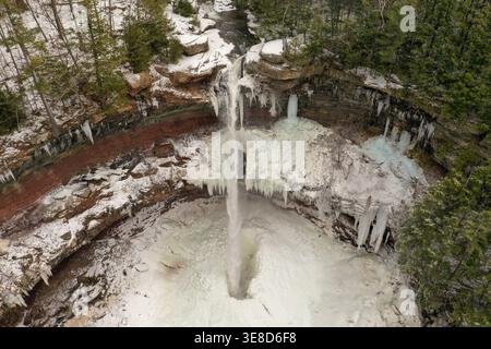 Cascata ghiacciata che si tuffa in una piscina ghiacciata con enormi ghiaccioli e scogliere innevate in una gola boscosa vicino a Ithaca New York in inverno. Foto Stock
