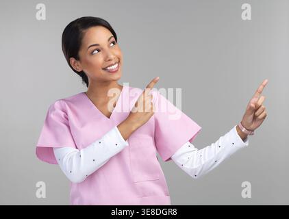 Medico, spazio e infermiere in studio con indicazioni, consigli per il benessere o mostrare informazioni con promozione. Assistenza sanitaria, donna o medico con mockup, servizio Foto Stock