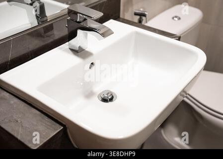 Lavandino del bagno pulito ed elegante con un elegante rubinetto cromato, ideale per progetti di interior design, marketing immobiliare e arredamento per la casa. Lig. Brillante Foto Stock