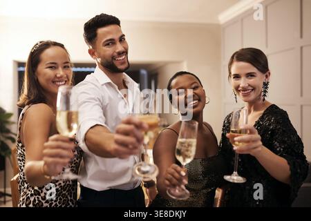 Ritratto, amici e bevande a casa con brindisi, Unione e festa per Capodanno. Notte, gente e applausi alla festa con champagne Foto Stock