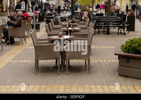 Tavoli da caffè all'aperto vuoti lungo City Street Foto Stock