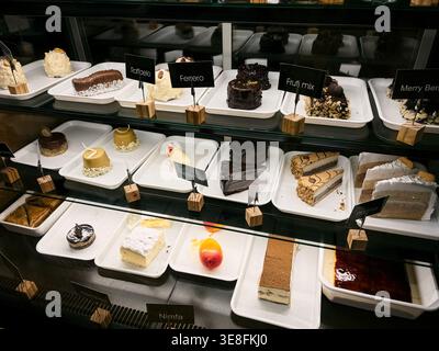 Varietà di torte e dessert esposti in una vetrina del caffè. Concetto di panetteria, scelta, cibo dolce ed esperienza del cliente. Foto Stock