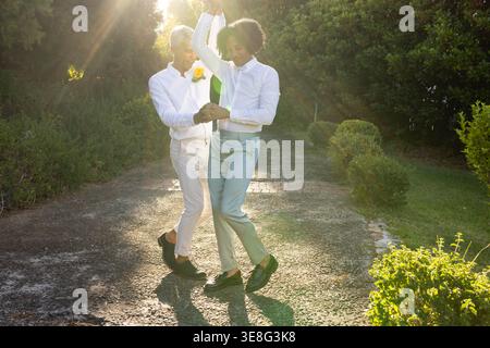 Coppia afroamericana che danzano su un sentiero pavimentato illuminato dal sole con scarpe da ballo gialle Foto Stock