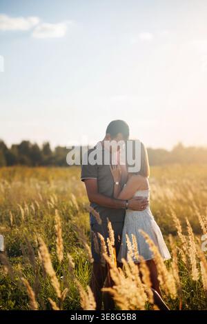 Un uomo e una donna condividono un momento intimo, stando vicini in un campo d'oro. La calda luce del sole mette in risalto il loro legame mentre si godono una S. Foto Stock