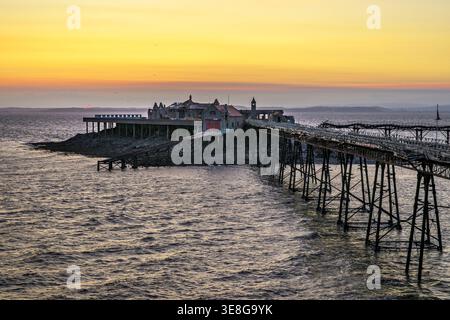 Il molo di Birnbeck si estende nel Canale di Bristol al tramonto a Weston-super-Mare, Somerset, Inghilterra, con una calda luce serale Foto Stock
