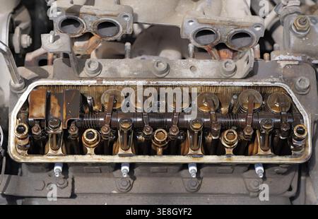 Chiusura di un motore aperto con coperchio delle valvole rimosso che mostra i bilancieri e i depositi pesanti di morchia d'olio, indicando l'usura e i problemi di manutenzione in un fou Foto Stock
