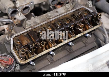Chiusura di un motore aperto con coperchio delle valvole rimosso che mostra i bilancieri e i depositi pesanti di morchia d'olio, indicando l'usura e i problemi di manutenzione in un fou Foto Stock