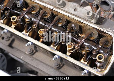 Chiusura di un motore aperto con coperchio delle valvole rimosso che mostra i bilancieri e i depositi pesanti di morchia d'olio, indicando l'usura e i problemi di manutenzione in un fou Foto Stock