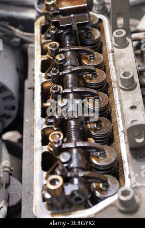 Chiusura di un motore aperto con coperchio delle valvole rimosso che mostra i bilancieri e i depositi pesanti di morchia d'olio, indicando l'usura e i problemi di manutenzione in un fou Foto Stock