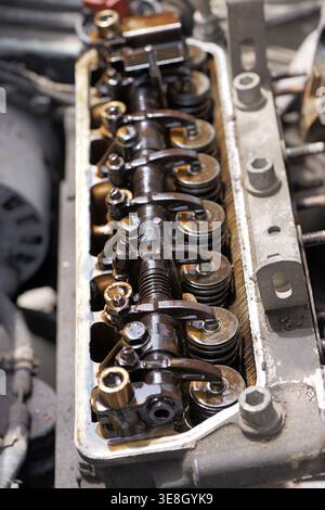 Chiusura di un motore aperto con coperchio delle valvole rimosso che mostra i bilancieri e i depositi pesanti di morchia d'olio, indicando l'usura e i problemi di manutenzione in un fou Foto Stock