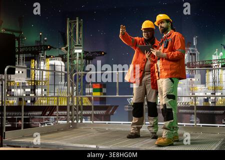 I membri dell'equipaggio della nave perforatrice lavorano insieme per gestire i flussi di lavoro operativi tramite tablet. Brainstorming dei colleghi della piattaforma offshore, documentando i report sulla sicurezza dei pericoli con l'applicazione del dispositivo Foto Stock