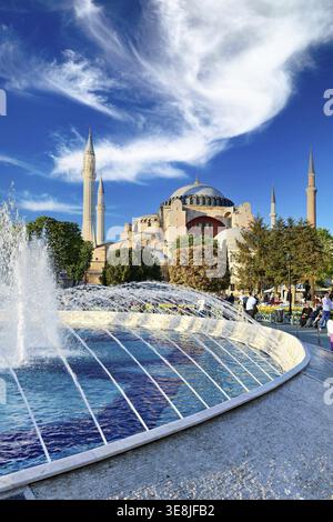 I visitatori esplorano la grande Moschea di Hagia Sophia a Istanbul. L'acqua spruzza da una fontana mentre il sole splende in questo sito storico Foto Stock