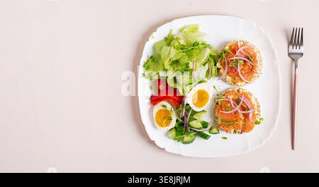 Colazione sana con salmone, uova e verdure fresche su sfondo leggero. Vista dall'alto, banner Foto Stock