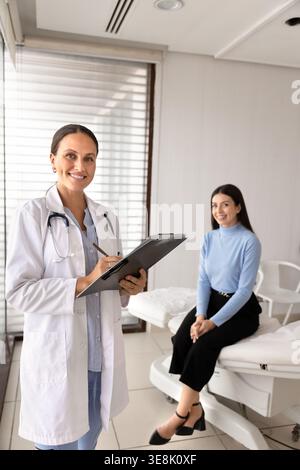 Ritratto del medico che tiene gli appunti, sorridente il paziente sullo sfondo Foto Stock
