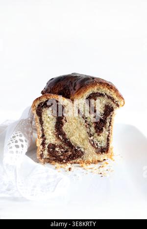 Fetta di tradizionale cozonac rumeno (o Babka al cioccolato) con ripieno di cacao e noci, isolato su sfondo bianco. Copia spazio. Foto Stock