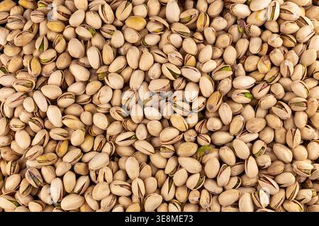 Vista dettagliata dell'abbondanza di pistacchi, con particolare attenzione all'esterno ruvido delle conchiglie e all'aspetto succulento dei chicchi esposti. Foto Stock