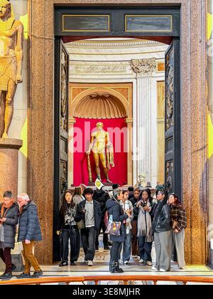Un gruppo di tour all'ingresso della sala Rotunda con una grande statua dorata di Ercole sullo sfondo all'interno dei Musei Vaticani Foto Stock