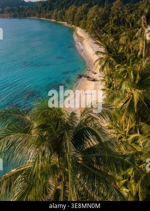 Scoprite il fascino tranquillo della spiaggia di Takhian a Koh Kood, Thailandia. Questo paradiso costiero mozzafiato offre morbide sabbie dorate, lussureggianti palme e acque turchesi, perfette per il relax. Foto Stock