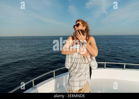 Madre e figlia felici che abbracciano di fronte allo yacht in mezzo all'oceano. Foto Stock