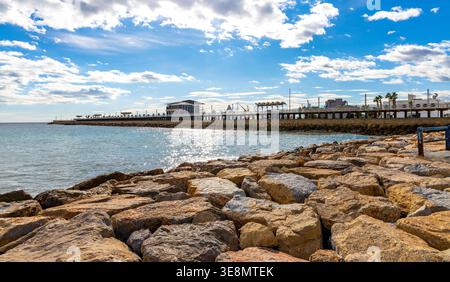 Alicante, Spagna - 20 gennaio 2026: Vista panoramica sul viale del molo che circonda il porto e sul porticciolo degli yacht sul porto marittimo del Mediterraneo Foto Stock