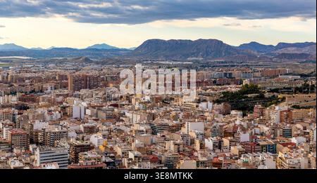 Alicante, Spagna - 20 gennaio 2026: Paesaggio urbano panoramico di Alicante con i quartieri urbani centrali e la catena montuosa della Sierra Fontcalent vista dal Monte Be Foto Stock