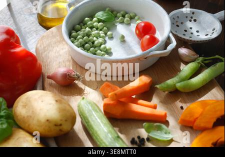Selezione di vivaci verdure della fattoria e utensili in metallo vintage su tavola da cucina rustica. La composizione in primo piano mostra ingredienti freschi di stagione Foto Stock