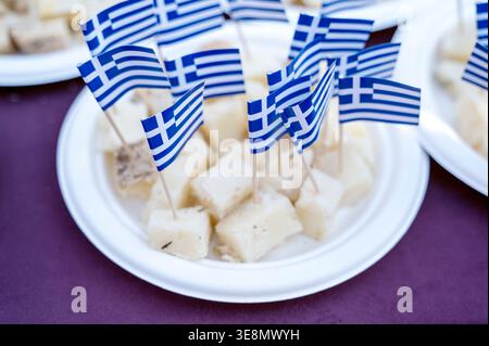 Cubetti di formaggio Feta su piatti bianchi decorati con piccole bandiere greche. Concetto di cucina mediterranea tradizionale, stuzzichini nazionali per le feste e aut Foto Stock