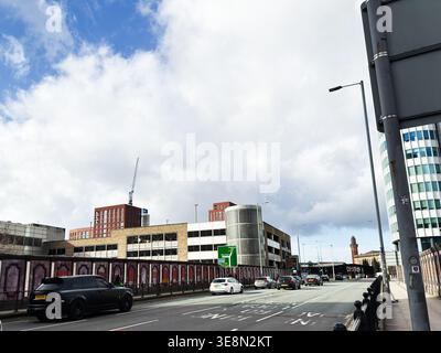 Manchester, Regno Unito - 22 febbraio 2026: Città trafficata di Manchester, Regno Unito, con auto, garage, gru e un cielo nuvoloso. Foto Stock