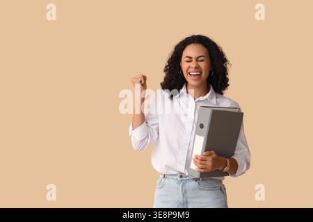 Felice candidato afroamericano con cartella su sfondo beige Foto Stock