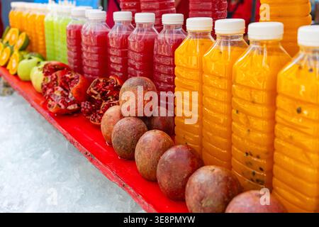 Colorati succhi di frutta tropicali, tra cui frutta della passione e melograno in bottiglia al mercato di Phuket Street, Thailandia. Luminose bevande tropicali. Sano Foto Stock