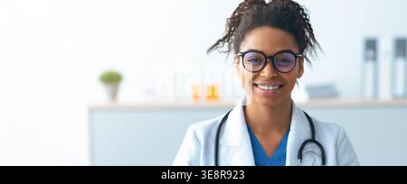 Donna Dottore che indossa gli occhiali sorride in un ambiente Bright Office Foto Stock