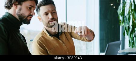 Due persone discutono di un progetto in un ambiente Office moderno durante il giorno Foto Stock