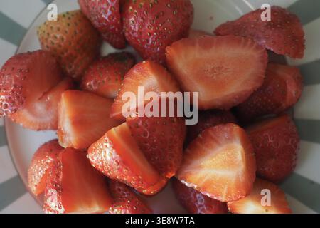 Fragole fresche tagliate e poste su un piatto bianco Foto Stock
