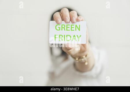 Carta di credito con l'iscrizione GREEN FRIDAY in mano femminile. Concetto per il business. Il concetto del movimento Make Friday Green Again. Ecologia Foto Stock