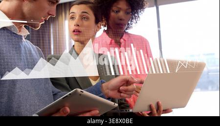 Come puntare il team che indossa abiti da ufficio e guarda notebook e tablet in un ufficio moderno con sovrapposizione di carte Foto Stock
