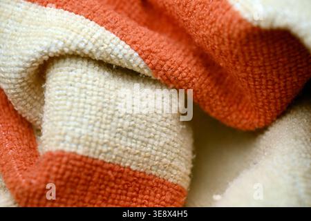 Asciugamano in lana a righe arancione e crema - primo piano con texture di tessuto increspato e sfondi morbidi sfocati Foto Stock