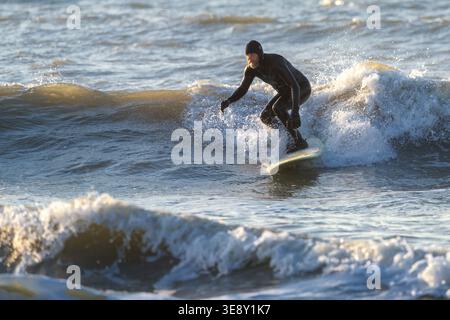 Folly Beach, USA - 21 marzo 2026: Un vecchio pensionato che si diverte a fare surf invernale al molo di Folly Beach vicino Charleston Foto Stock