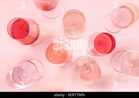 Varietà di vini rosa, bicchieri da vino in posizione orizzontale, diverse tonalità e tinte, su sfondo rosa, molti bicchieri da vino Foto Stock