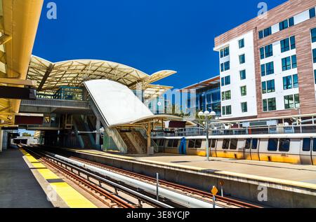 Vista delle piattaforme e del moderno design architettonico della stazione di transito Millbrae con un treno bart e alloggi urbani vicino a San Francisco a Califo Foto Stock