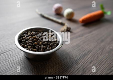 Alimenti secchi Cat in ciotola con giocattoli sfocati sullo sfondo, cura degli animali domestici e concetto di stile di vita, attenzione selettiva con spazio di copia per la pubblicità Foto Stock